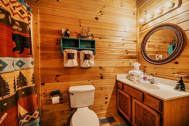 bathroom featuring vanity, toilet, and wooden walls