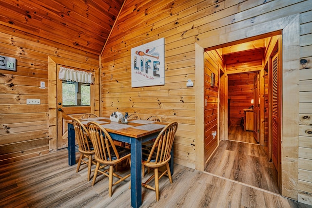 dining space with hardwood / wood-style floors, vaulted ceiling, wooden ceiling, and wood walls