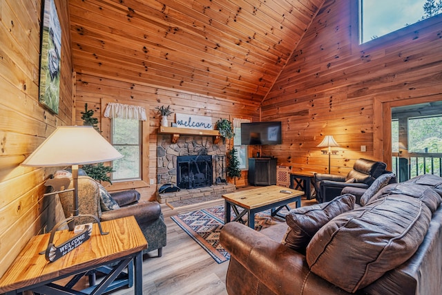 living room featuring a fireplace, a wealth of natural light, wooden walls, and light wood-type flooring