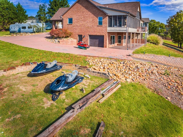 rear view of house featuring a sunroom, a garage, a patio, and a lawn