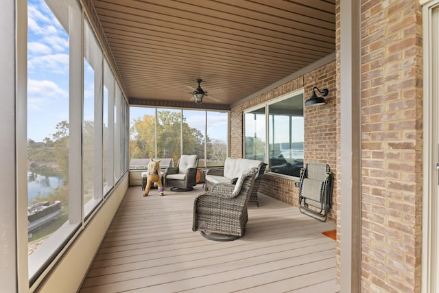 sunroom / solarium featuring ceiling fan and a water view