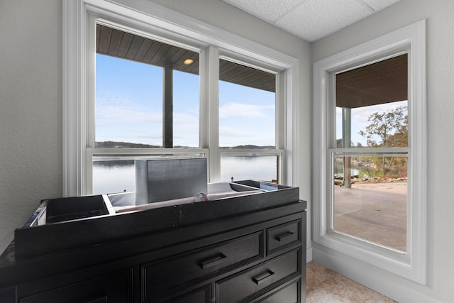 interior space with a paneled ceiling and a water view