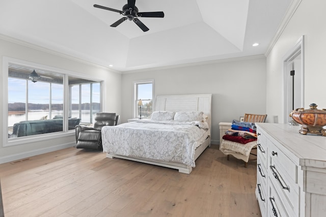 bedroom with a raised ceiling, ceiling fan, a water view, and light hardwood / wood-style floors