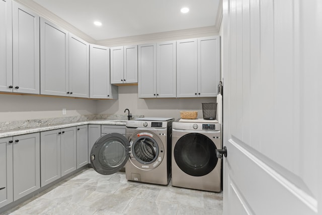 clothes washing area featuring washer and dryer, sink, and cabinets