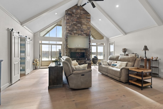 living room featuring a barn door, plenty of natural light, and high vaulted ceiling