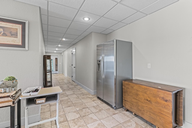 hallway featuring a drop ceiling and light tile patterned floors