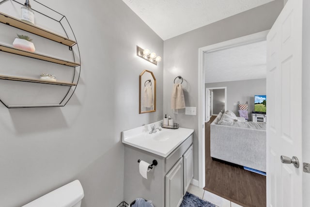 bathroom with toilet, vanity, ensuite bath, a textured ceiling, and tile patterned floors