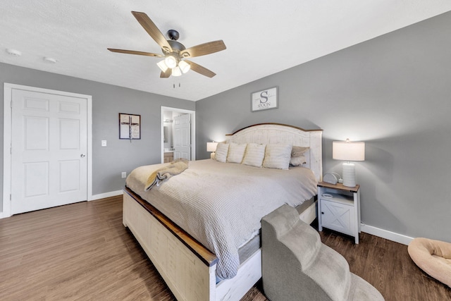 bedroom with a ceiling fan, connected bathroom, baseboards, and wood finished floors