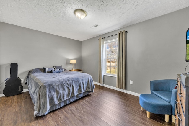 bedroom featuring a textured ceiling, wood finished floors, visible vents, and baseboards