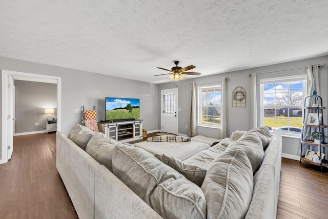 living area featuring dark wood-style flooring, a textured ceiling, and baseboards