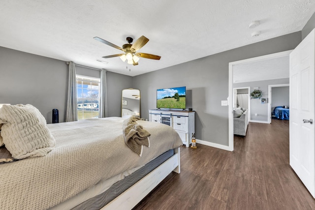 bedroom with dark wood-style floors, a ceiling fan, baseboards, and a textured ceiling