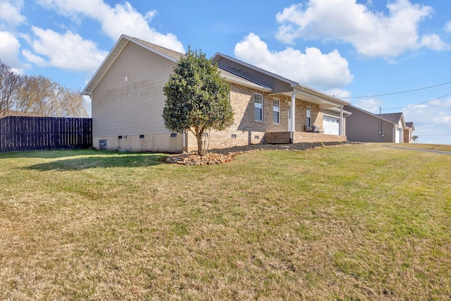 exterior space featuring brick siding, a yard, crawl space, fence, and a garage