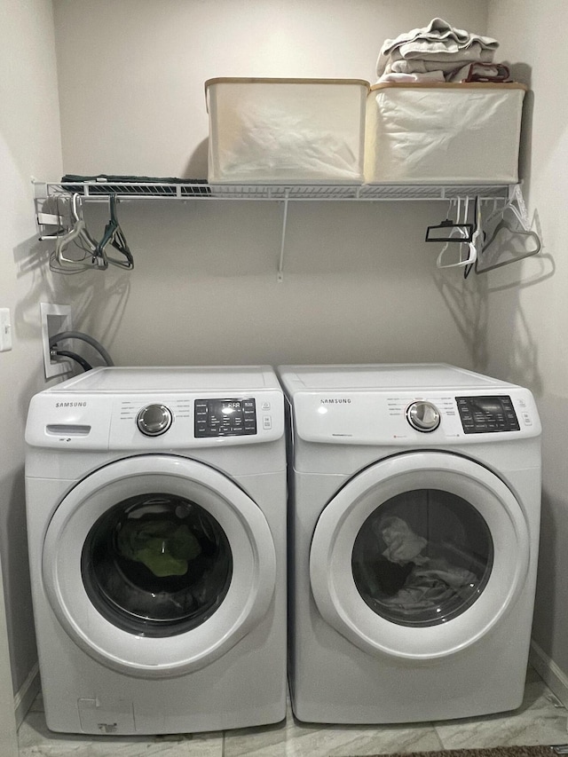 washroom featuring baseboards, marble finish floor, washer and dryer, and laundry area