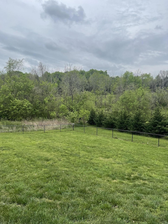 view of yard featuring fence, a rural view, and a view of trees