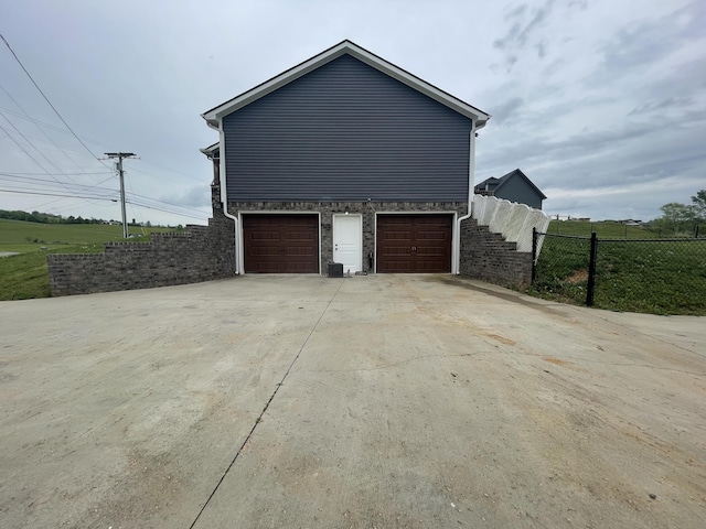 view of home's exterior with an attached garage, fence, and driveway
