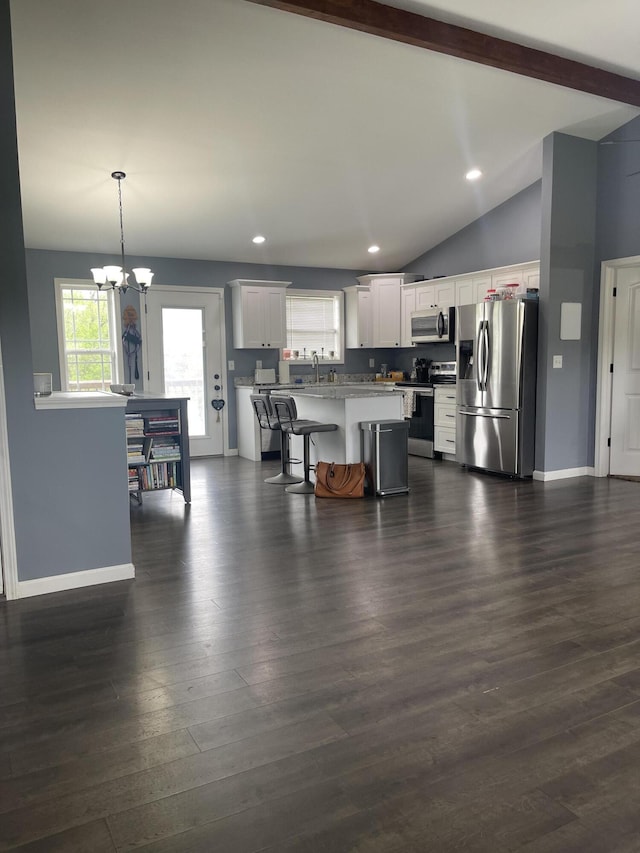 kitchen with a kitchen breakfast bar, vaulted ceiling with beams, white cabinetry, baseboards, and appliances with stainless steel finishes