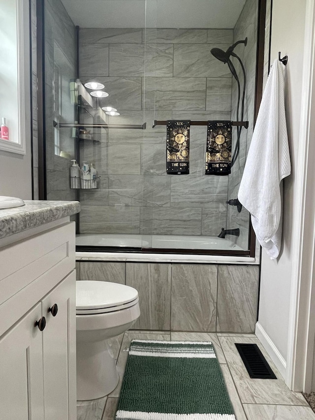 full bathroom featuring tiled shower / bath combo, visible vents, toilet, and vanity