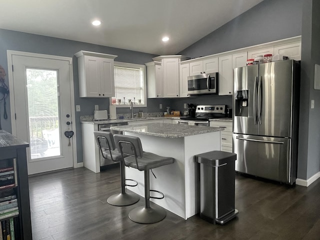 kitchen with white cabinets, stainless steel appliances, a kitchen island, and dark wood-style flooring