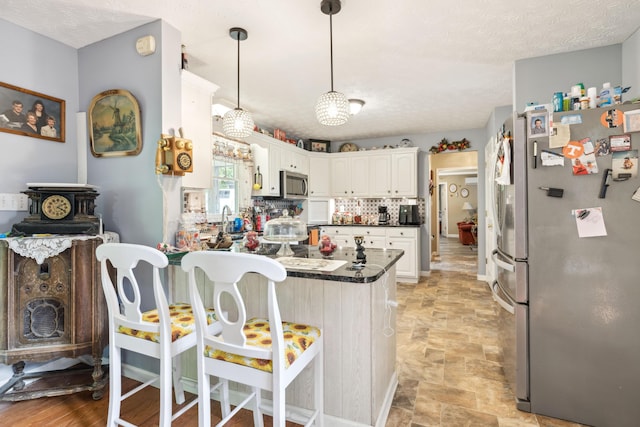 2895 Looney Rd, Parrottsville, TN 37843 - kitchen featuring stainless steel appliances, a peninsula, dark countertops, a kitchen bar, and hanging light fixtures