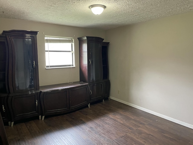 empty room featuring dark hardwood / wood-style floors and a textured ceiling