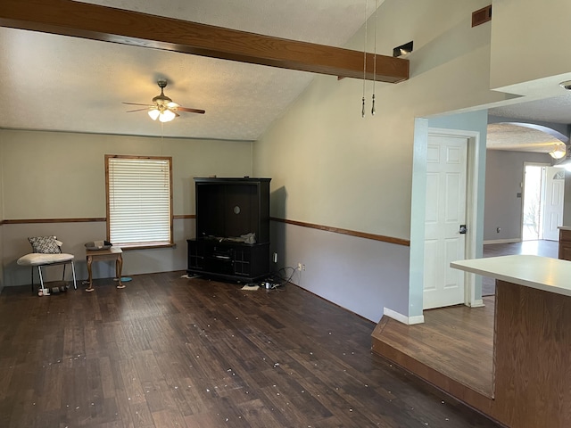 misc room with a textured ceiling, vaulted ceiling with beams, dark hardwood / wood-style floors, and ceiling fan