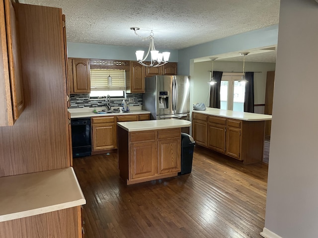 kitchen featuring stainless steel refrigerator with ice dispenser, a center island, sink, black dishwasher, and hanging light fixtures