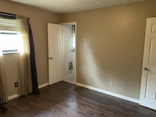 unfurnished room featuring a textured ceiling, heating unit, and dark hardwood / wood-style floors