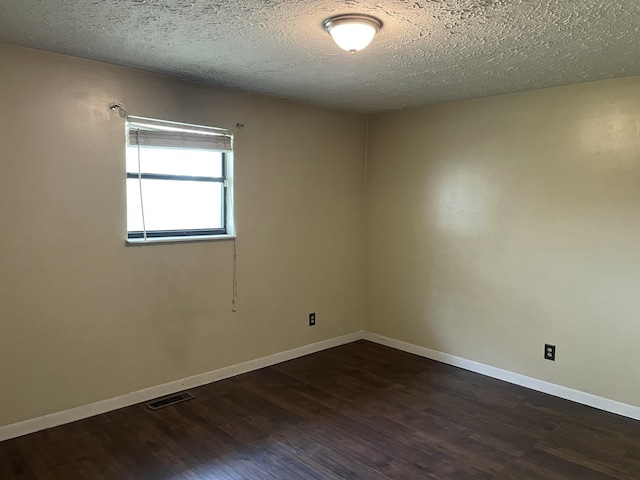 empty room with a textured ceiling and dark hardwood / wood-style floors