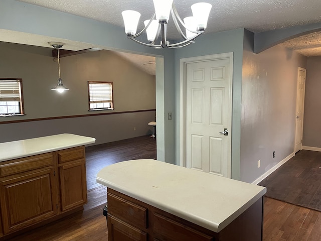 kitchen with a center island, dark wood-type flooring, hanging light fixtures, a notable chandelier, and a textured ceiling