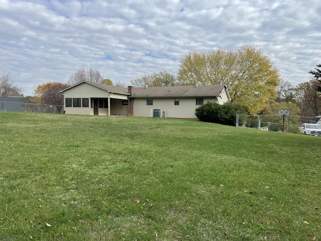 rear view of property featuring a lawn and a sunroom