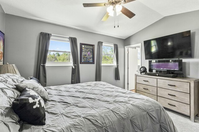 bedroom with ceiling fan, vaulted ceiling, and light carpet
