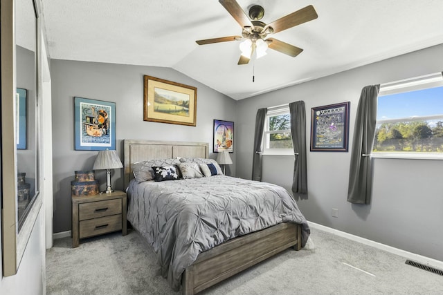carpeted bedroom with lofted ceiling, baseboards, a ceiling fan, and visible vents