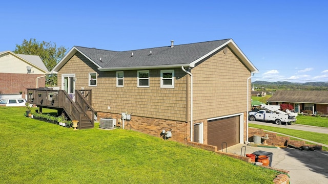back of house featuring a yard, central air condition unit, driveway, roof with shingles, and a garage