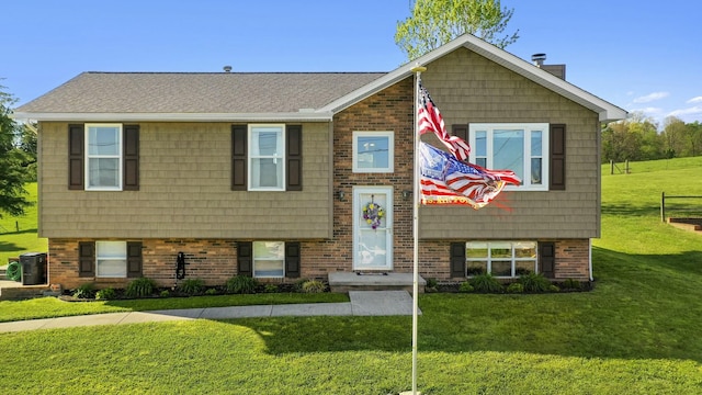 bi-level home with a front lawn, brick siding, and roof with shingles