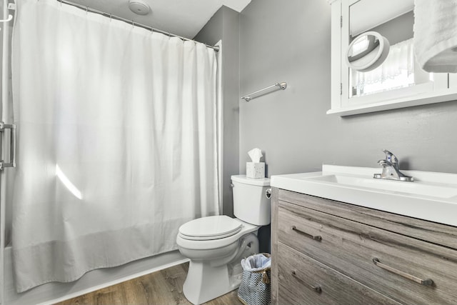 bathroom featuring toilet, shower / tub combo with curtain, vanity, and wood finished floors