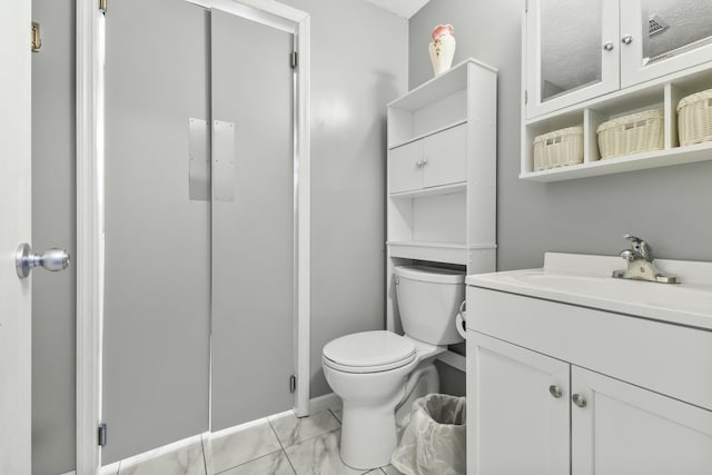 bathroom with marble finish floor, toilet, and vanity