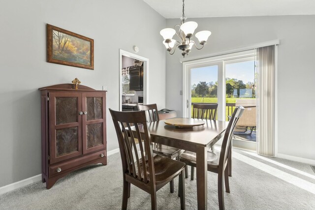 dining room with baseboards, lofted ceiling, light colored carpet, and a notable chandelier
