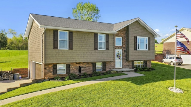 split foyer home with a garage, a shingled roof, a front yard, and concrete driveway
