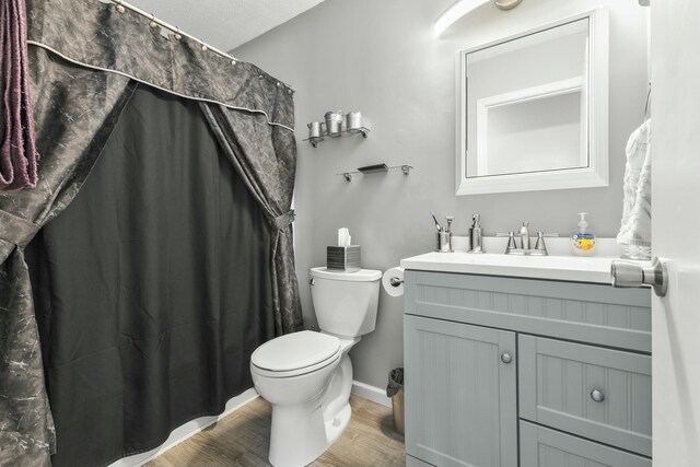 bathroom with baseboards, wood finished floors, toilet, and vanity