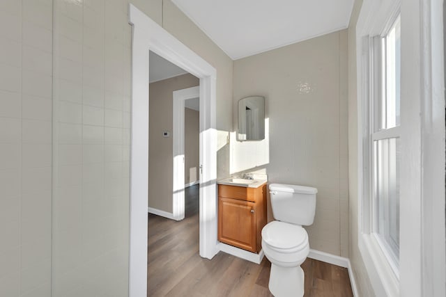 bathroom featuring vanity, baseboards, wood finished floors, and toilet