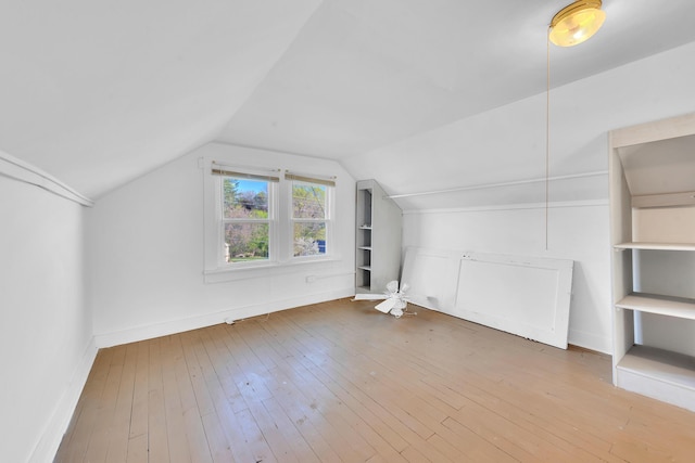 bonus room with wood-type flooring, baseboards, vaulted ceiling, and built in features
