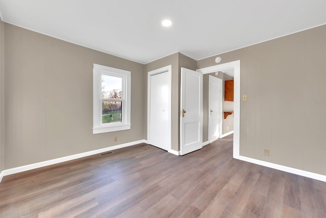 unfurnished bedroom featuring dark wood-type flooring, baseboards, visible vents, and a closet