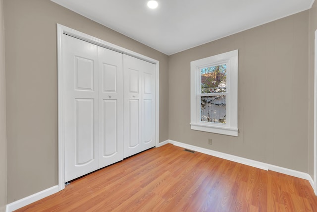 unfurnished bedroom featuring baseboards, a closet, light wood-style flooring, and visible vents