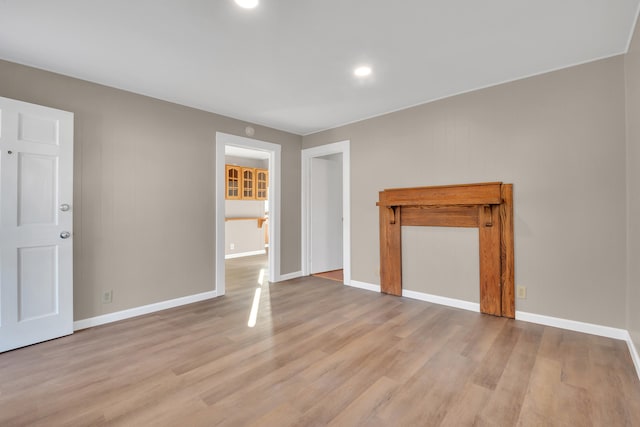 unfurnished living room with light wood-type flooring and baseboards