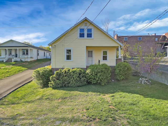 bungalow featuring a porch, a front lawn, and brick siding