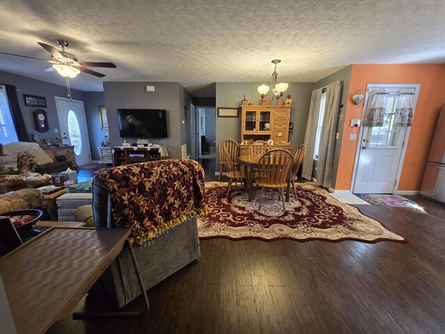 living room featuring baseboards, a textured ceiling, wood finished floors, and ceiling fan with notable chandelier