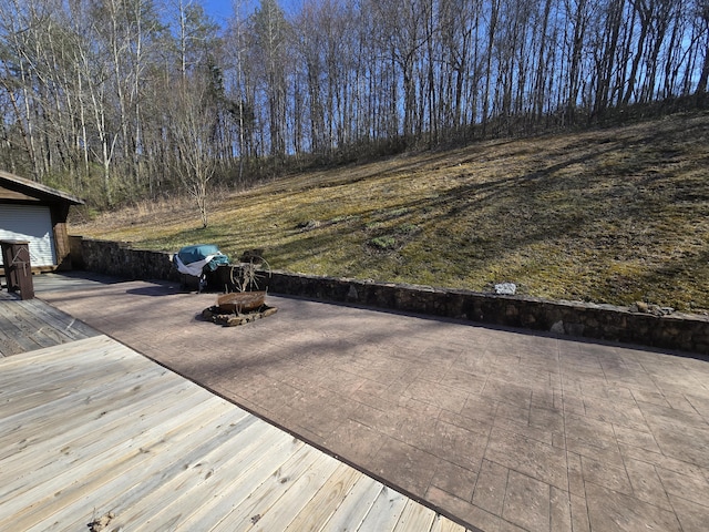 wooden terrace featuring a patio area, decorative driveway, a fire pit, and grilling area