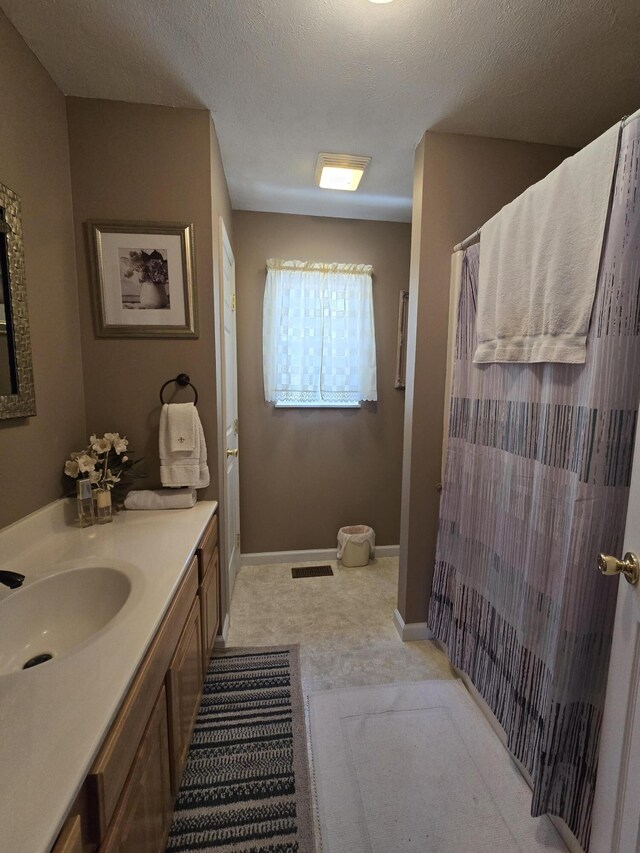 full bath featuring visible vents, baseboards, vanity, a shower with curtain, and a textured ceiling