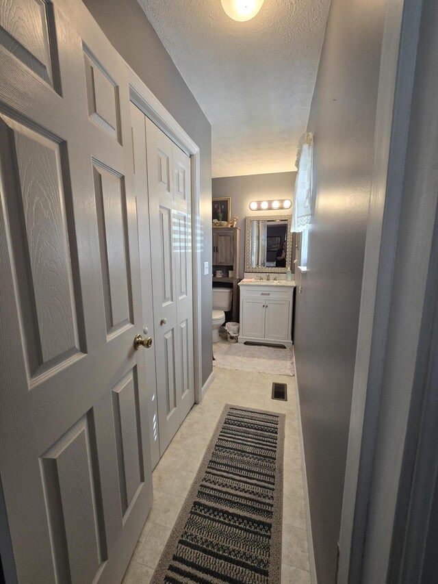 bathroom with visible vents, toilet, a textured ceiling, tile patterned flooring, and vanity