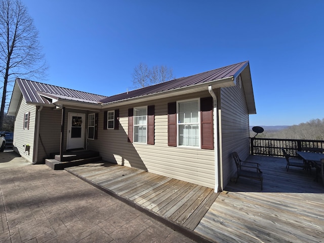 back of property featuring metal roof, a deck, and entry steps